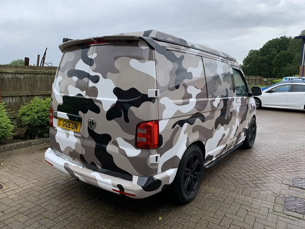A camouflage print van parked in a driveway.