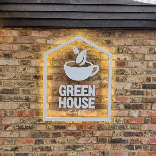 A sign on a brick wall that says green house cafe.