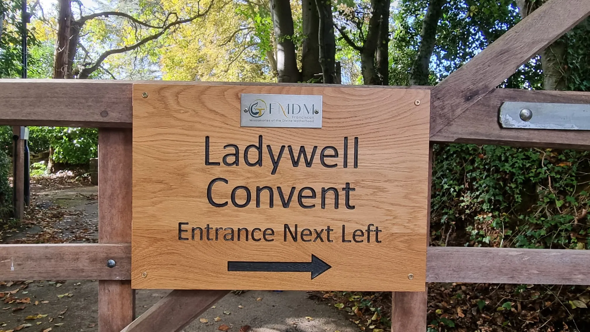 a sign that says ladywell convention entrance next to a wooden gate
