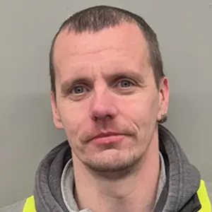 A man in a yellow vest is looking at the camera.