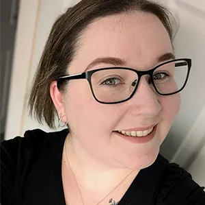 A woman with glasses smiling for the camera.