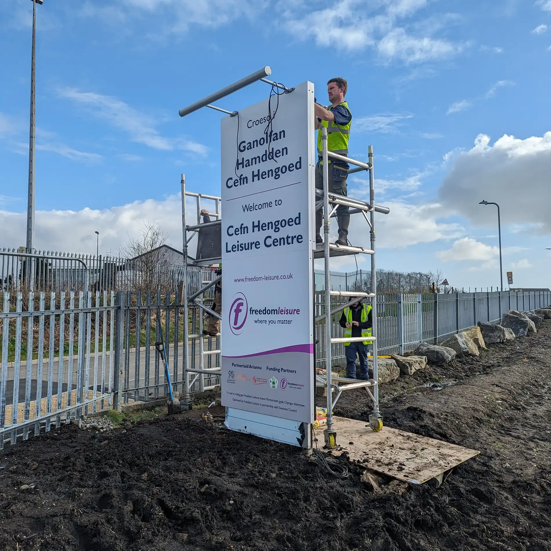 sign on a scaffolding with a man standing on it