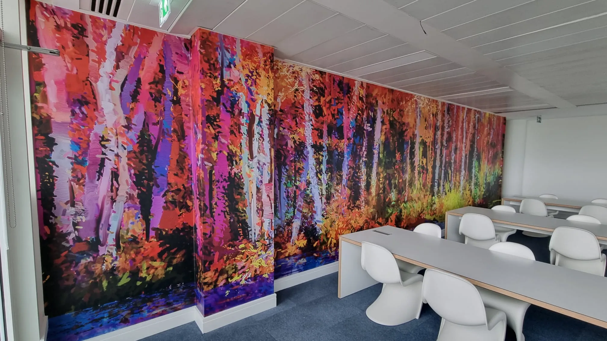 brightly colored wall mural in a conference room with white chairs